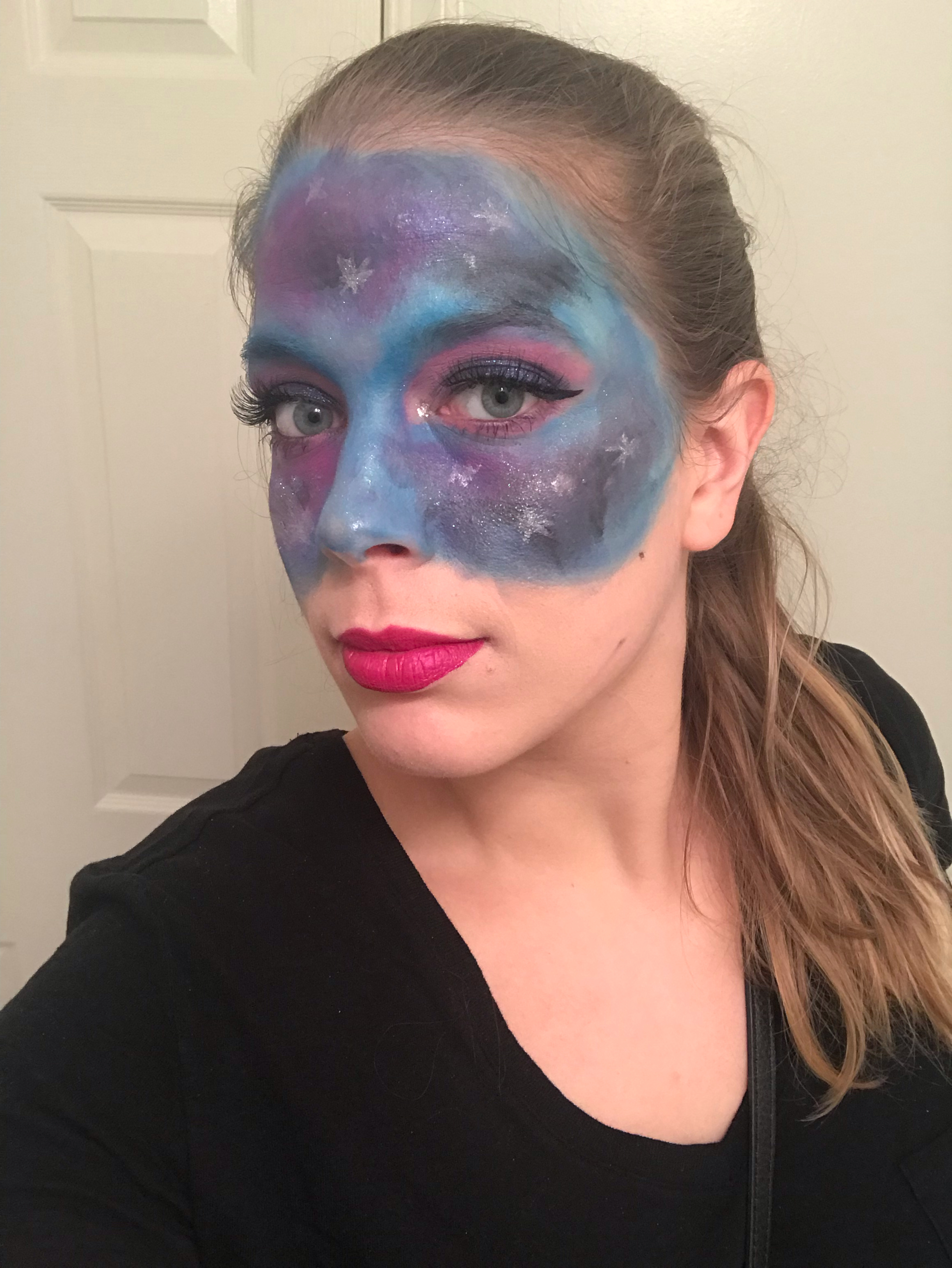 Lindsey with her upper half of her face covered in blue, pink, and black colors being an interpretation of a galaxy.